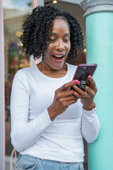 Fototapeta na wymiar Smiling woman using smart phone in front of building
