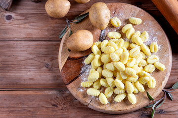 Wooden board with tasty gnocchi and spices on a wooden table. Top view