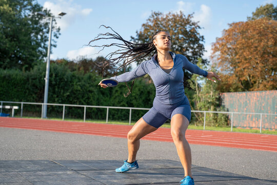 Female athlete training discus throwing at stadium - Powered by Adobe