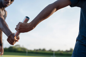 Two athletes passing relay baton during race