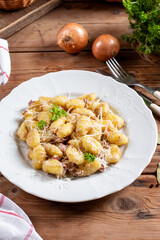 Plate of delicious gnocchi with creamy sauce on a wooden table