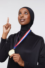 Studio shot of young woman in hijab wearing gold medal © Cultura Creative