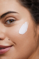 Close-up of young woman applying face cream