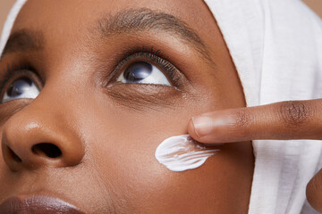 Studio shot of young woman in white hijab applying face cream