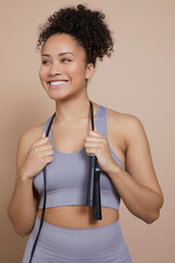Studio portrait of smiling athletic woman with jump rope