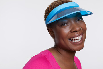 Studio portrait of smiling woman wearing blue sun visor