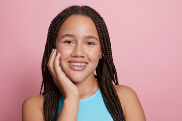 Studio portrait of smiling girl with braids and decorative stickers on face © Cultura Creative