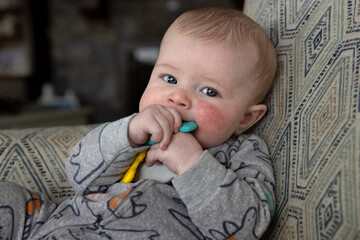 Four month old baby boy with a toy in his mouth.