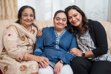Obraz premium Family portrait with down syndrome woman on sofa at home