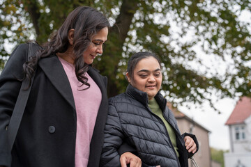 Mother walking with down syndrome daughter in residential district