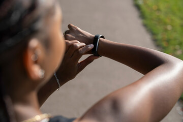 Young woman checking watch after jogging - obrazy, fototapety, plakaty