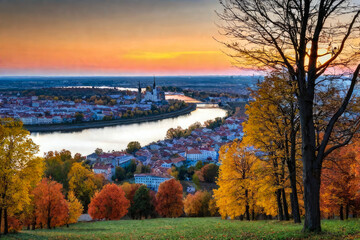 Autumn landscape on the background of the city. The river and the yellow trees, the reflection of the city in the water