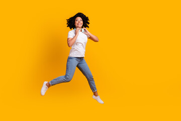 Fototapeta na wymiar Full length photo of funky pretty lady dressed white t-shirt jumping enjoying music headphones empty space isolated yellow color background