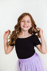 Close-up portrait of cute blonde curly kid girl 6-7 years old in black t-shirt on white studio background.