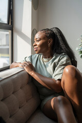 Portrait of young woman looking through window at home