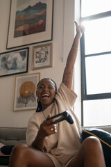 Excited young woman playing video games while sitting on sofa at home