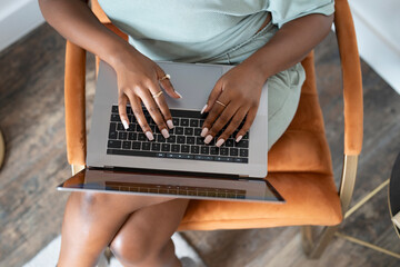 Young woman using laptop while sitting in armchair at home