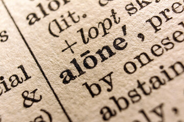 Word "alone" printed on book page, macro close-up