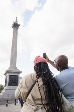 UK, London, Happy mature couple photographing Nelson's Column while visiting city
