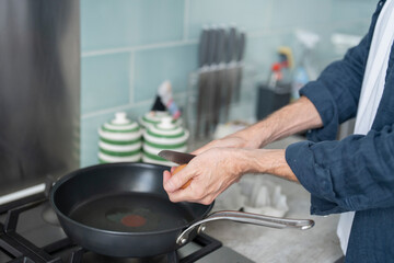 Close-up of man breaking egg into pan