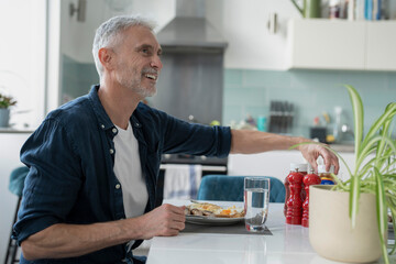 Smiling mature man eating breakfast at home © Cultura Creative
