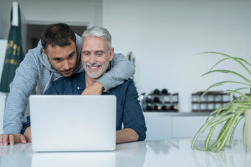 Male couple using laptop at home