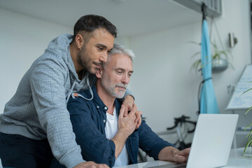 Male couple using laptop at home