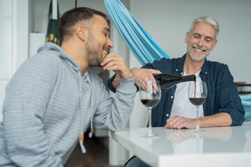 Fototapeta na wymiar Male couple pouring red wine at home