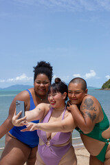 Group of cheerful women taking selfie on beach