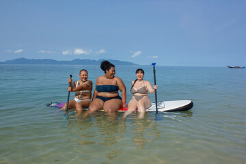 Group of cheerful women sitting on paddleboard