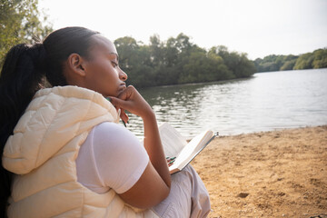 Woman reading book on lakeshore