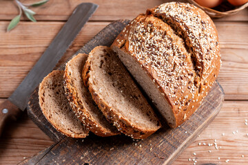 Homemade DIY, organic, healthy bread made of whole rye and wheat flour and seeds: sesame, chia, coriander , laid out on a wooden table.