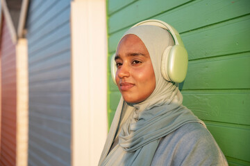 Portrait of Muslim woman listening to music on sunny day