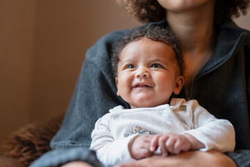 Smiling baby girl sitting on mothers lap © Cultura Creative