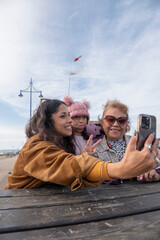 Grandmother, mother and daughter taking selfie with smart phone