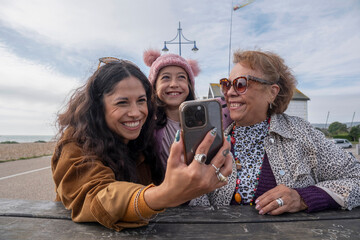 Grandmother, mother and daughter taking selfie with smart phone