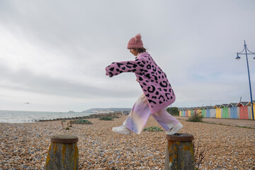 Girl jumping on groyne on beach