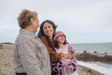 Grandmother, mother and daughter looking at sea on cloudy day