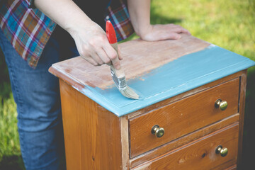 Painting a wooden furniture outdoors, an eco-friendly re-use business.