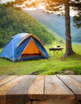 Wooden table in blur camping tent and grass field. Cool and relaxing concept. For product display montage or key visual layout design. space for text