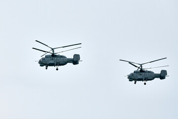 Two Russian military helicopters armed with missiles flies in blue sky, airborne mission of...