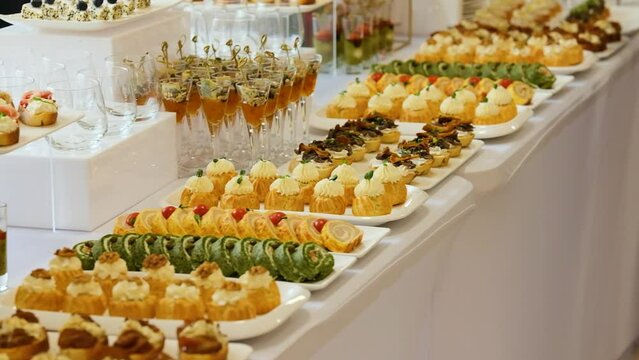 Catering service on banquet table with canape snacks in restaurant or hotel. Decorated food set on birthday, wedding celebration or business conference event venue.