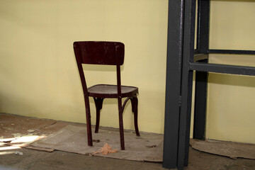 A wooden chair in front of a stucco wall	