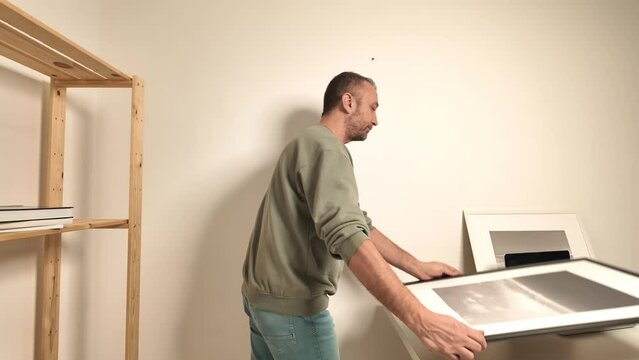 Man hanging pictures on the wall.	
