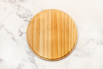 Plato redondo de madera sobre un fondo de mármol blanco rústico. Vista superior y de cerca. Copy space