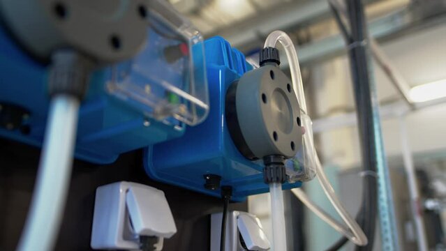 Flocculant dosing pump device with thin pipes and sockets in factory workshop closeup. Modern wastewater treatment facility tools