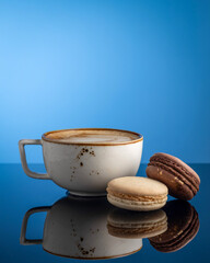 cappuccino mug with macaroon on blue background