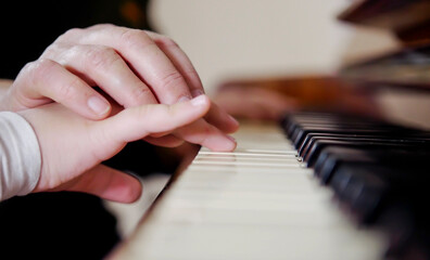 Experienced hand of the old music teacher helps the child student. Experienced master piano hand...