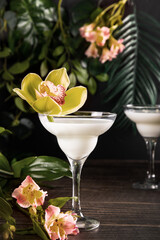 Cold pina colada white exotic cocktail with decorated orchid flower. Tropical vibes.