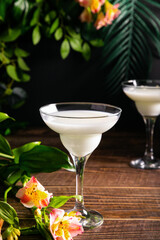 Cold pina colada white exotic cocktail with decorated flowers and palm leaves Tropical vibes.